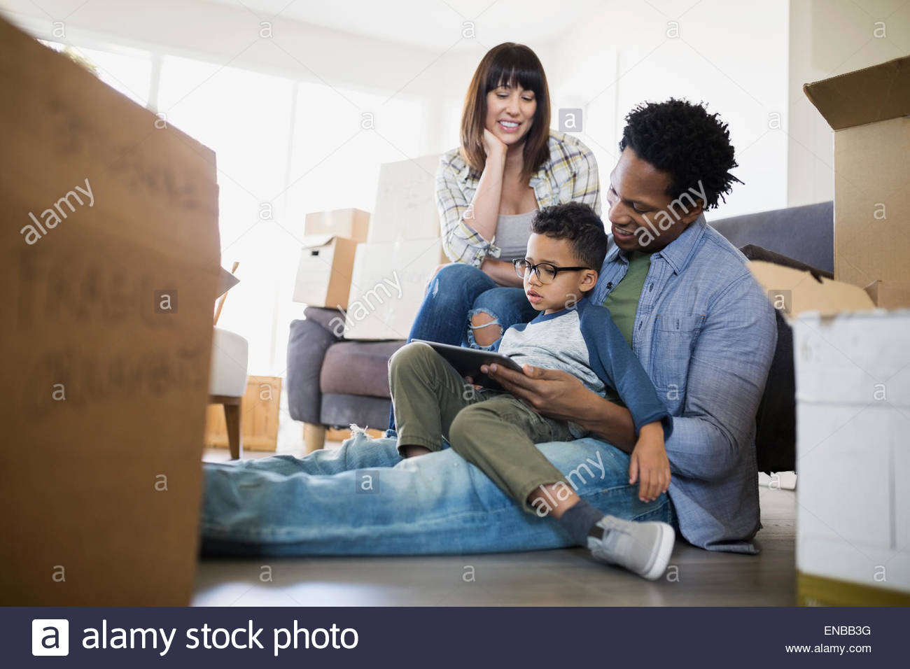 Moving boxes surrounding family using digital tablet Stock Photo