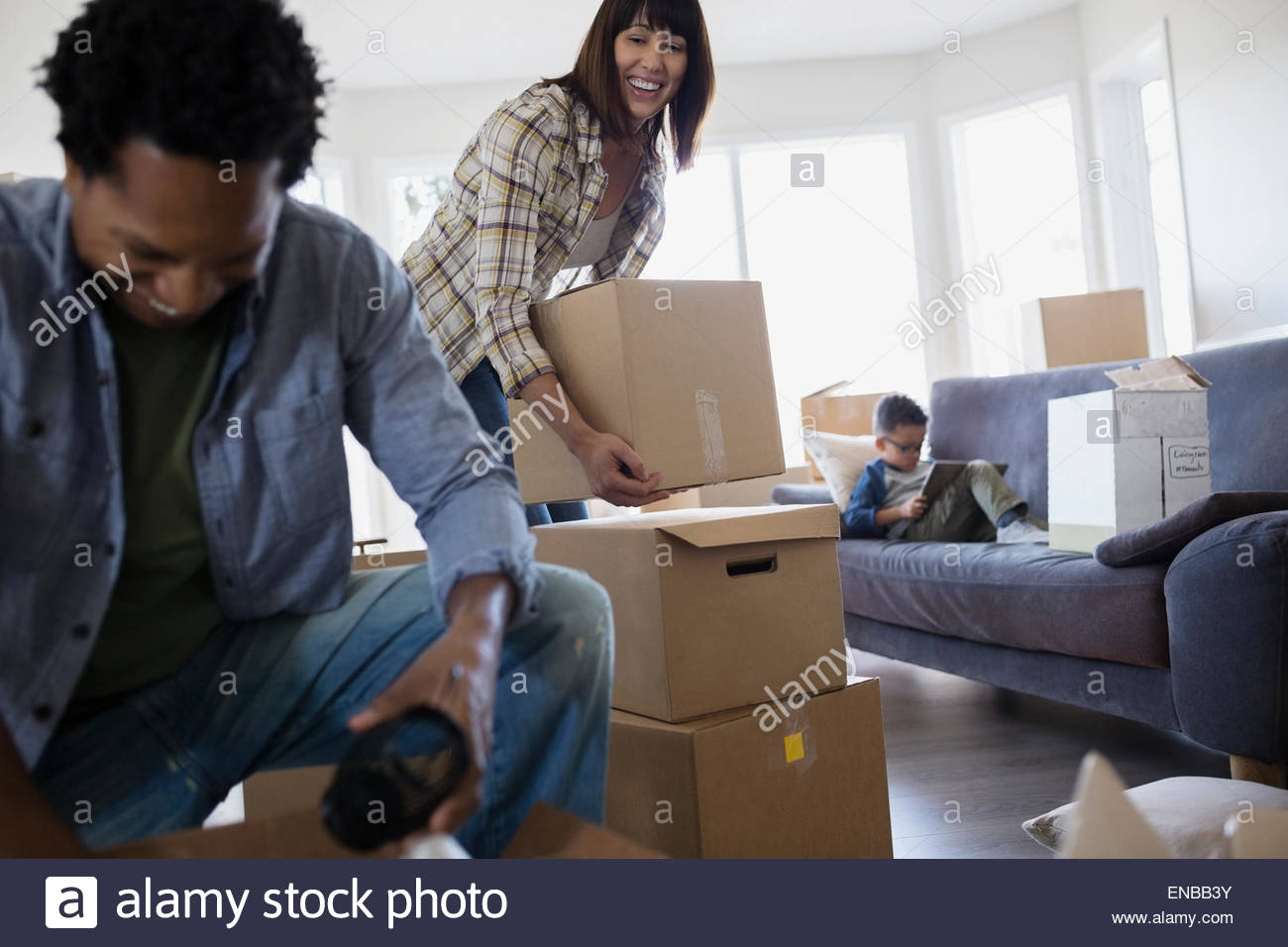 Family unpacking moving boxes in living room Stock Photo