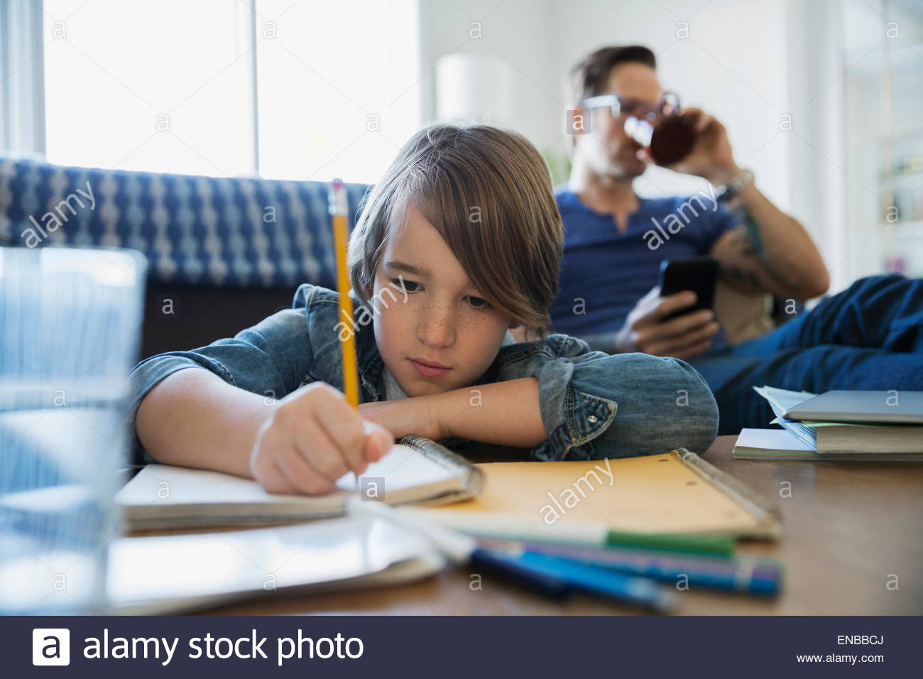 Son doing homework with father in background Stock Photo