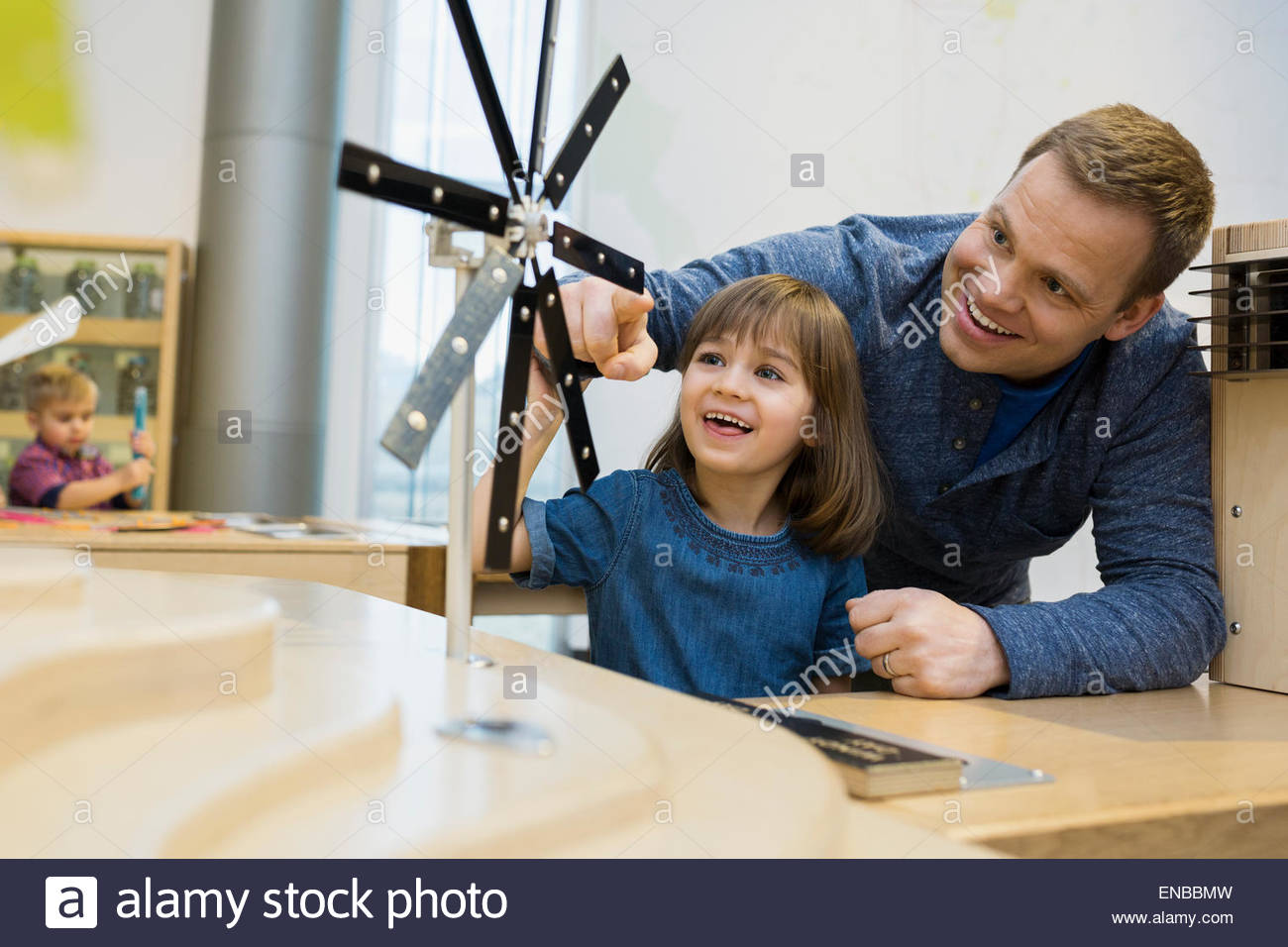Father daughter playing metal wind turbine science center Stock Photo