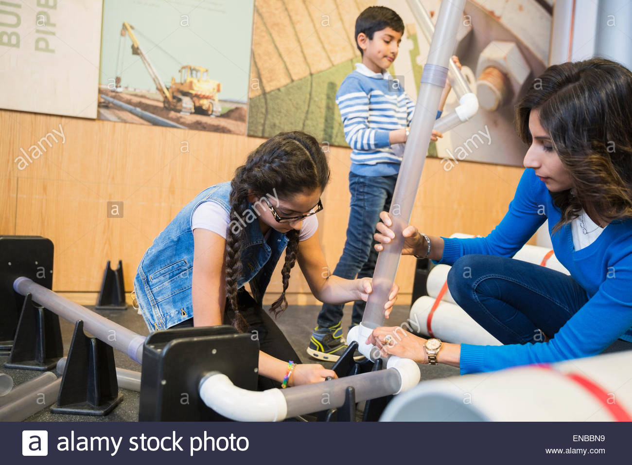 Family assembling pipeline at science center Stock Photo