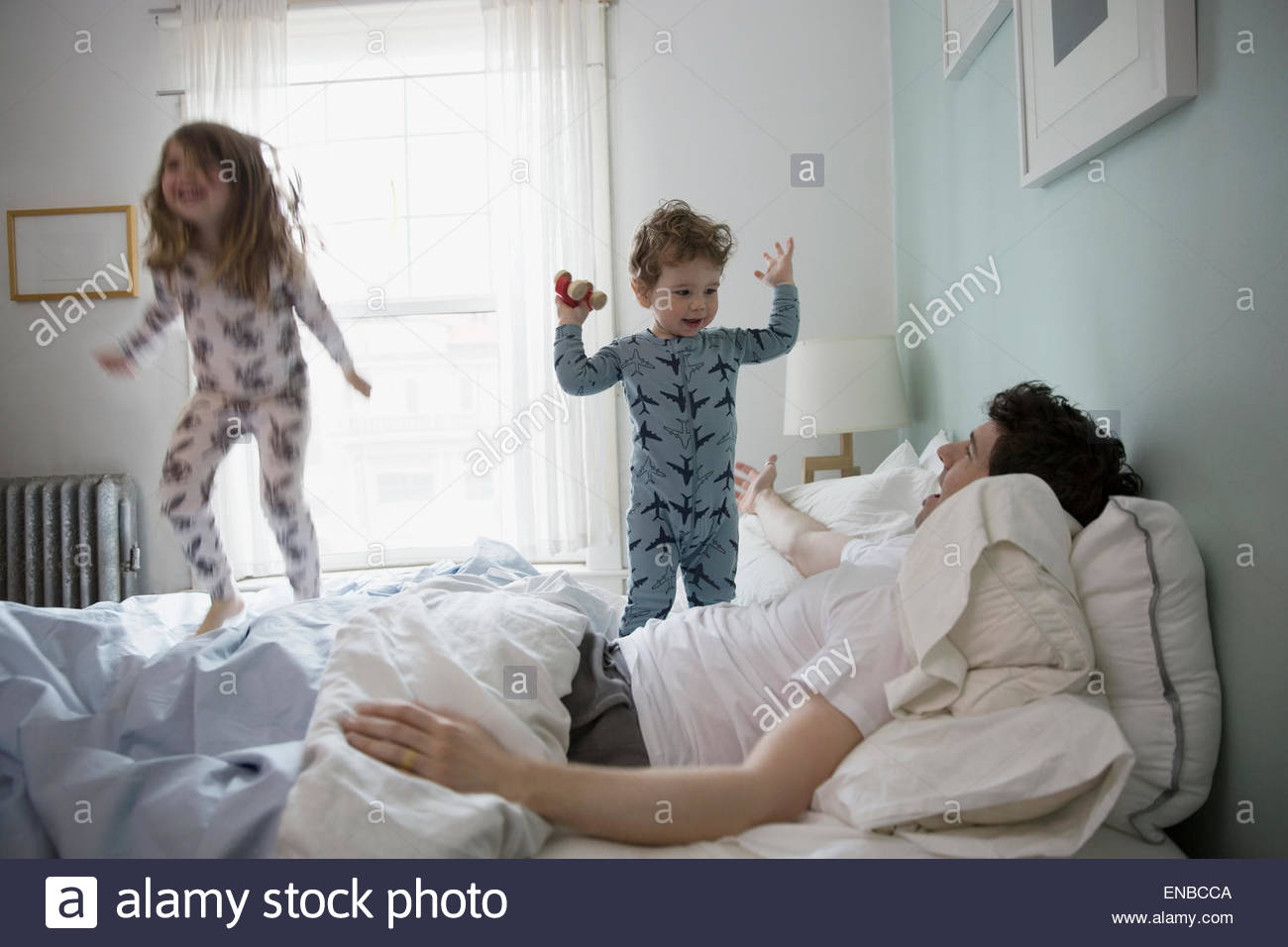 Father and children in pajamas playing in bed Stock Photo