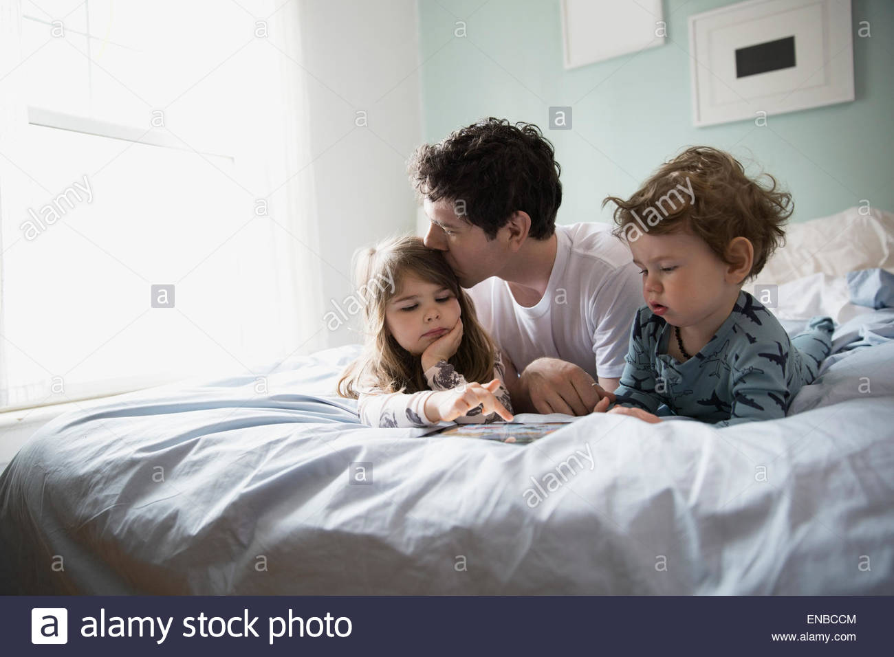 Father and children using digital tablet in bed Stock Photo