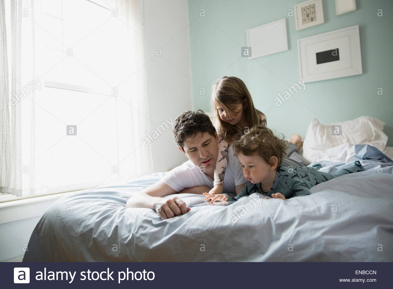 Father and children using digital tablet in bed Stock Photo