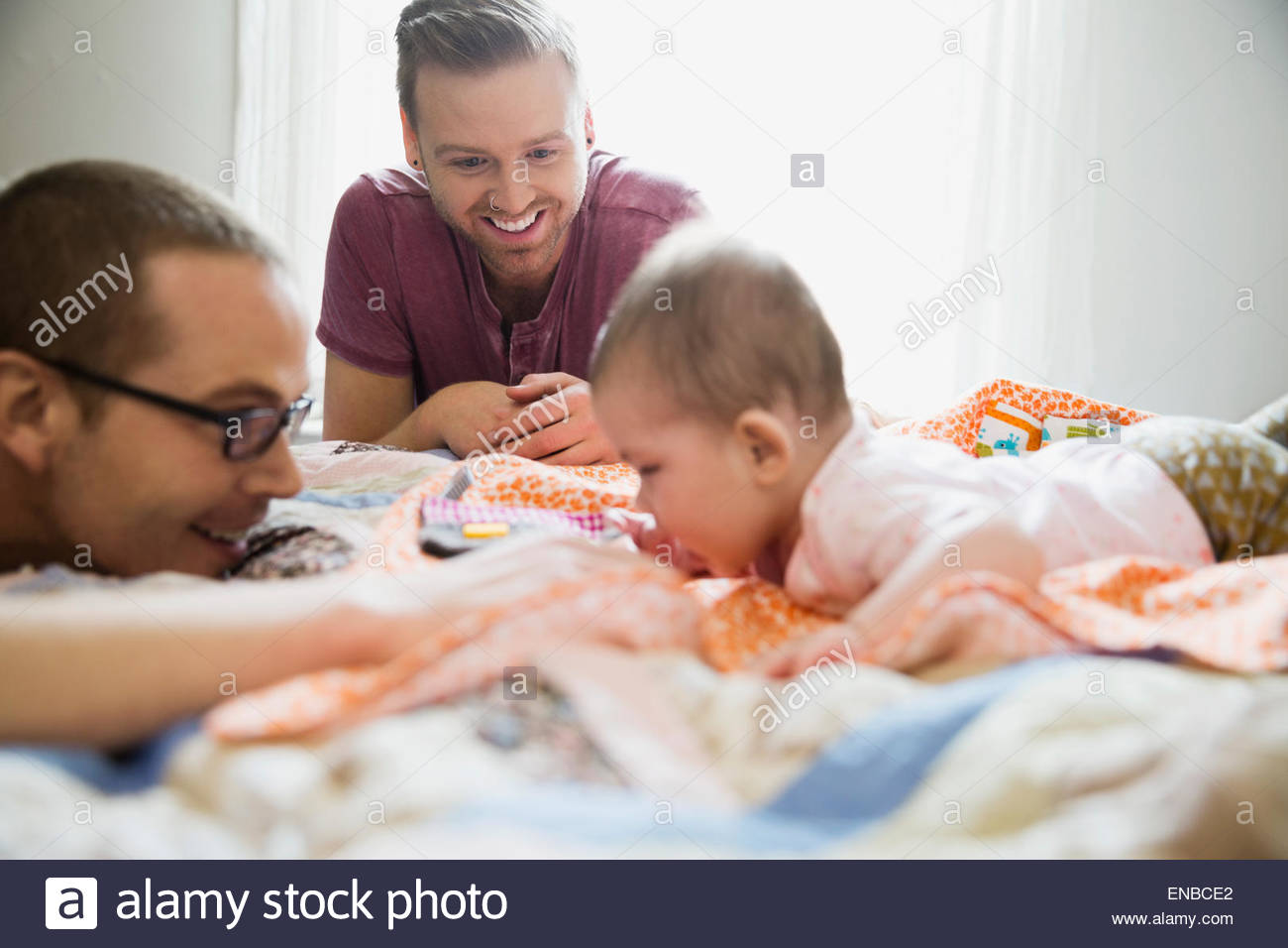 Homosexual couple playing with baby on bed Stock Photo