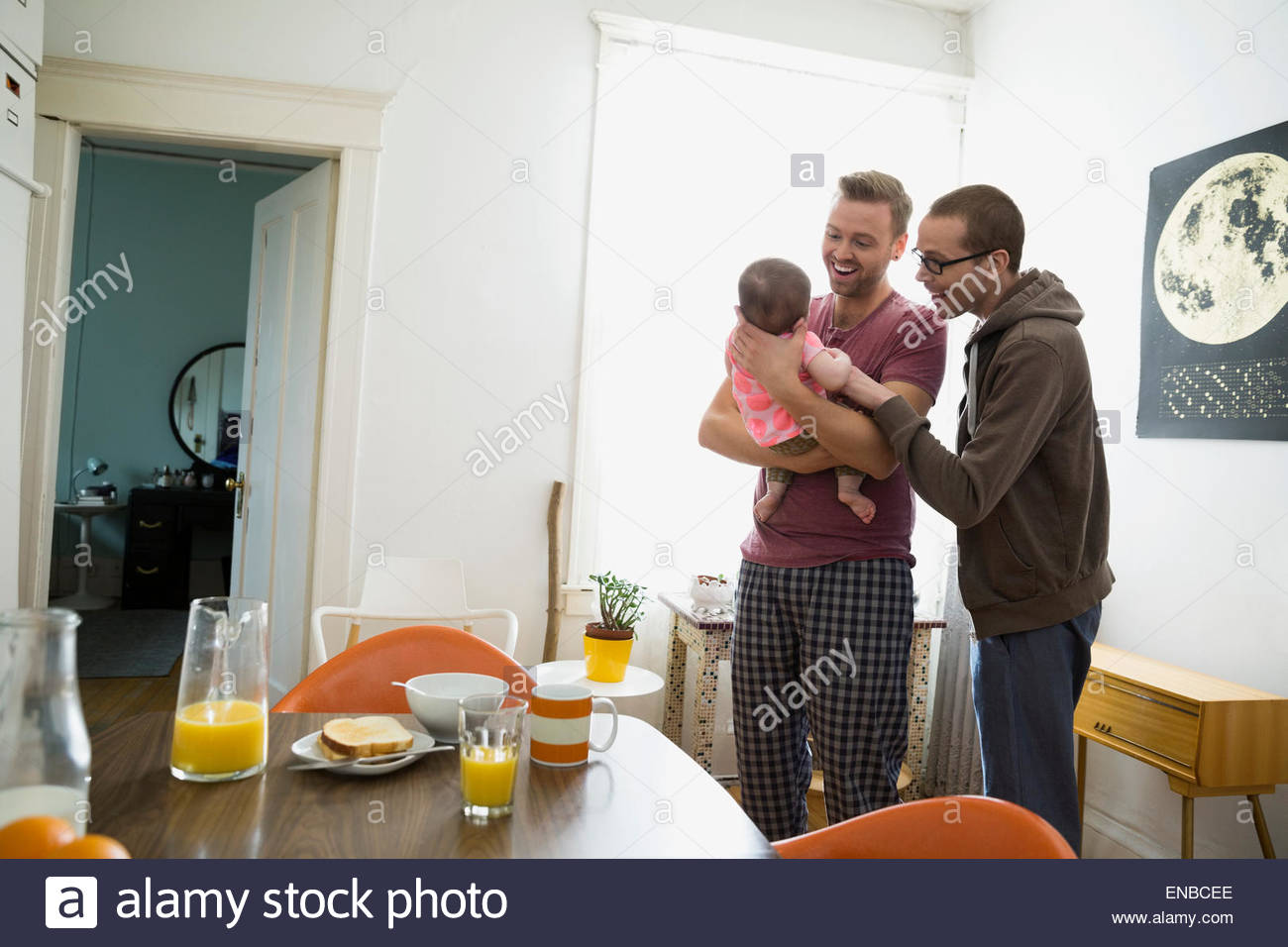 Homosexual couple with baby daughter at window Stock Photo