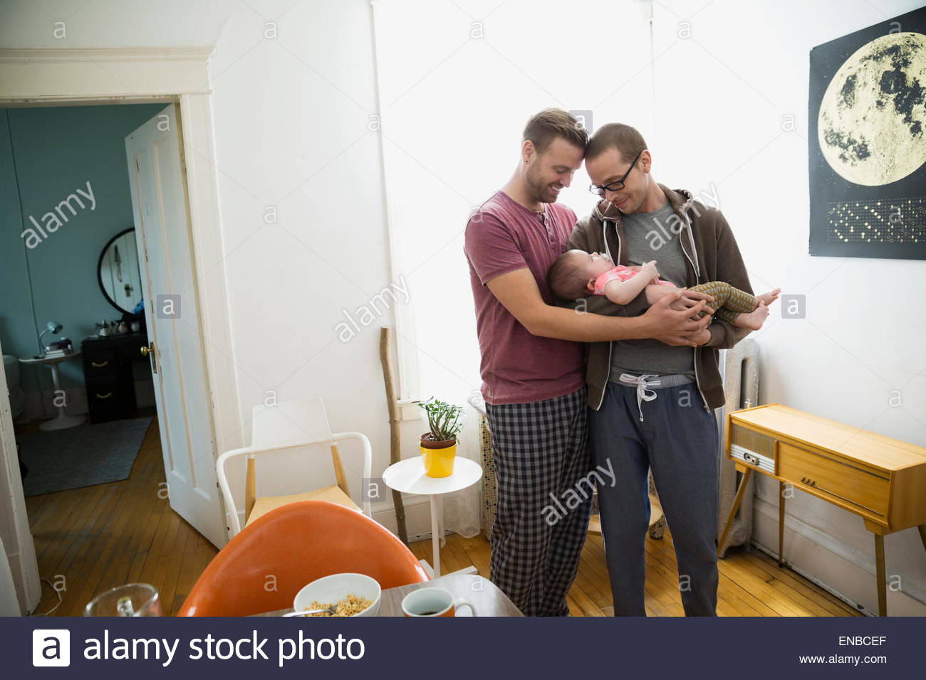 Homosexual couple cradling baby daughter Stock Photo