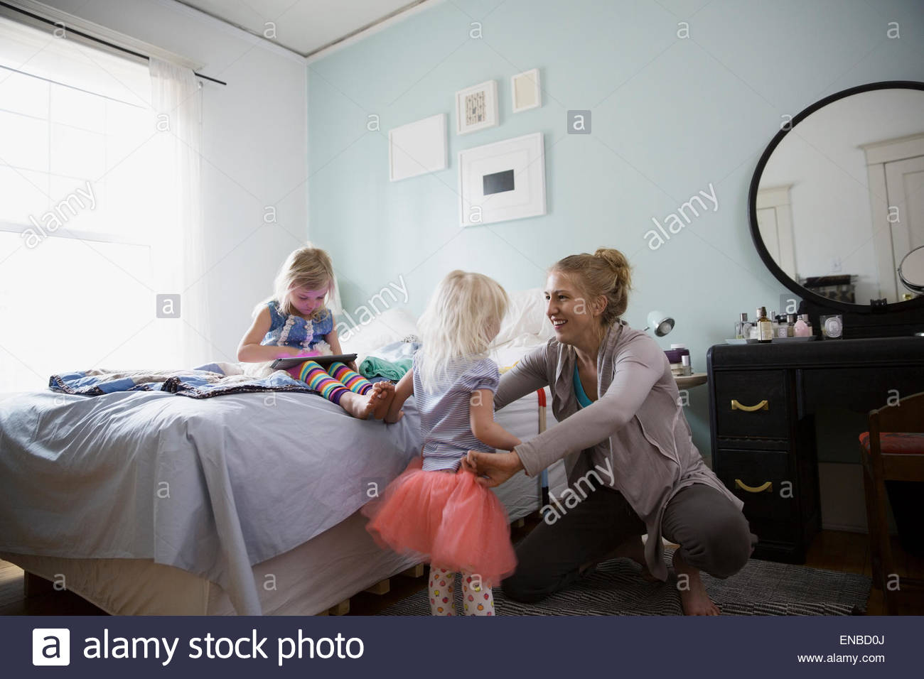 Mother putting tutu on daughter in bedroom Stock Photo - Alamy