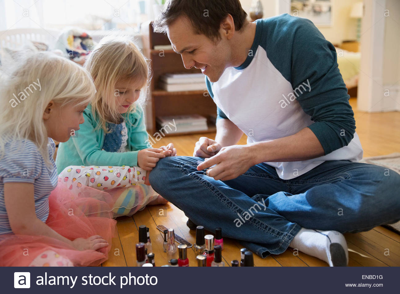 Father painting daughter fingers with fingernail polish Stock Photo