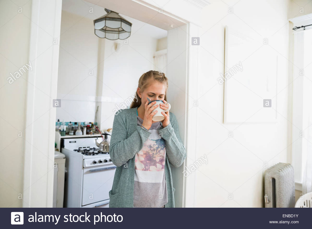 Woman sipping coffee in kitchen doorway Stock Photo