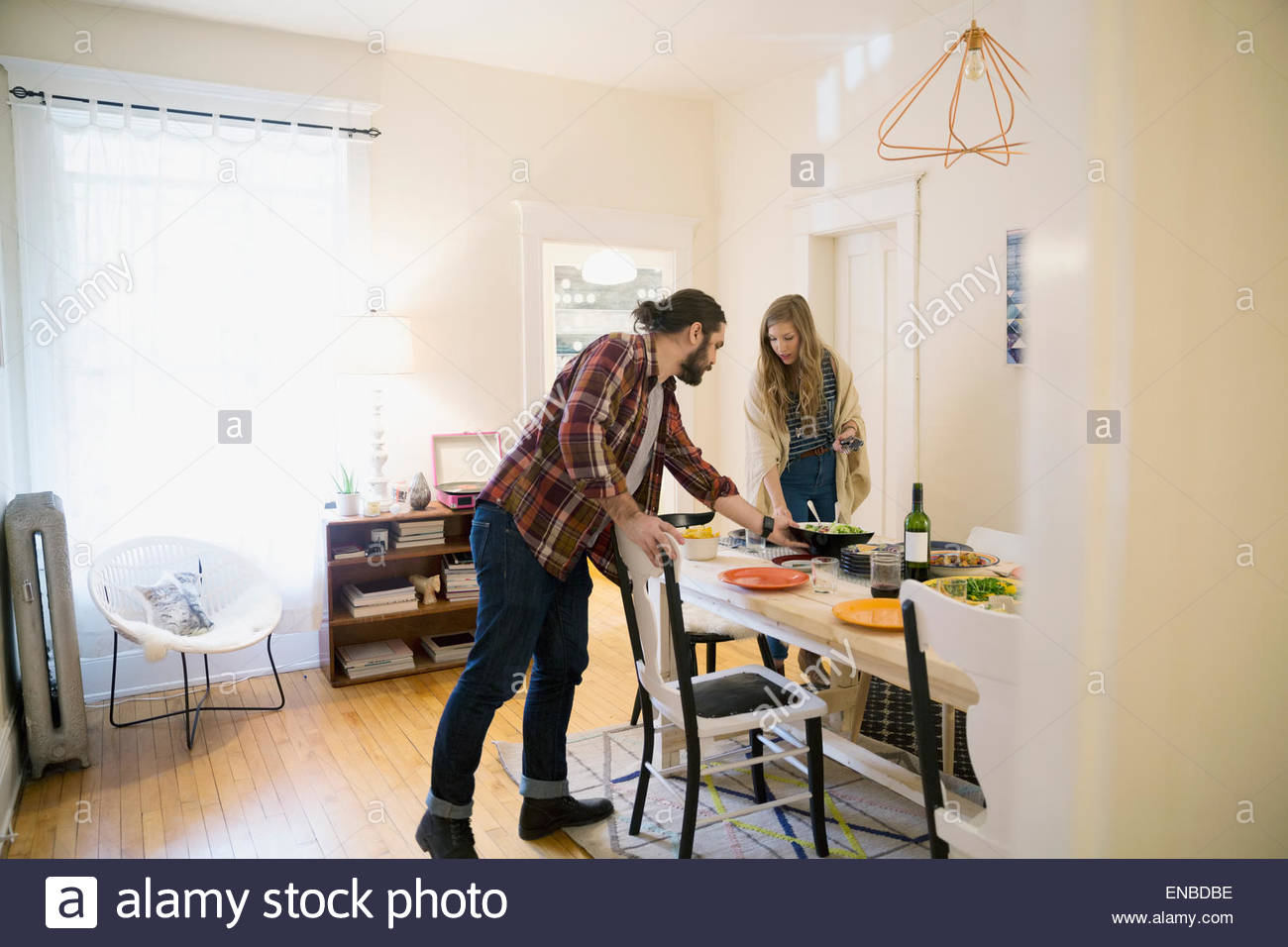 Couple setting the table in dining room Stock Photo