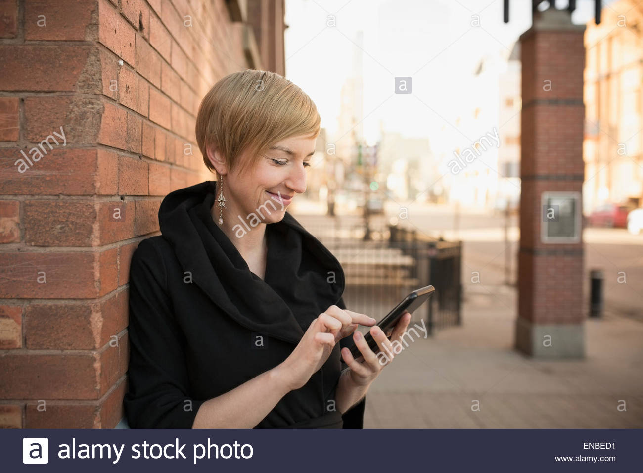 Smiling woman texting cell phone on urban street Stock Photo