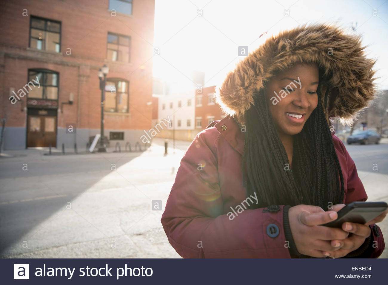 Woman in fur hood jacket texting urban street Stock Photo