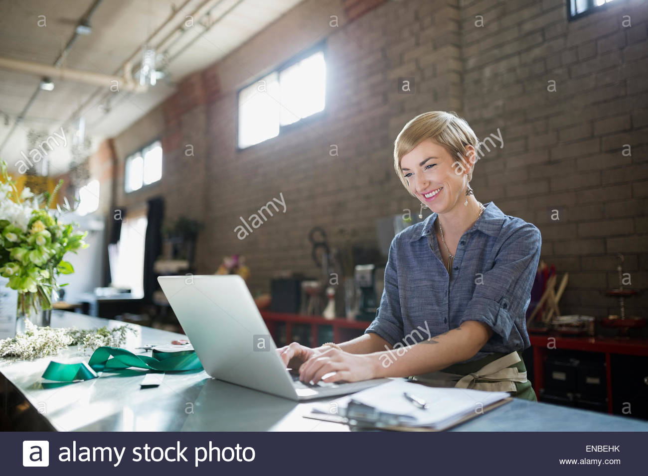 Smiling florist working at laptop in flower shop Stock Photo - Alamy