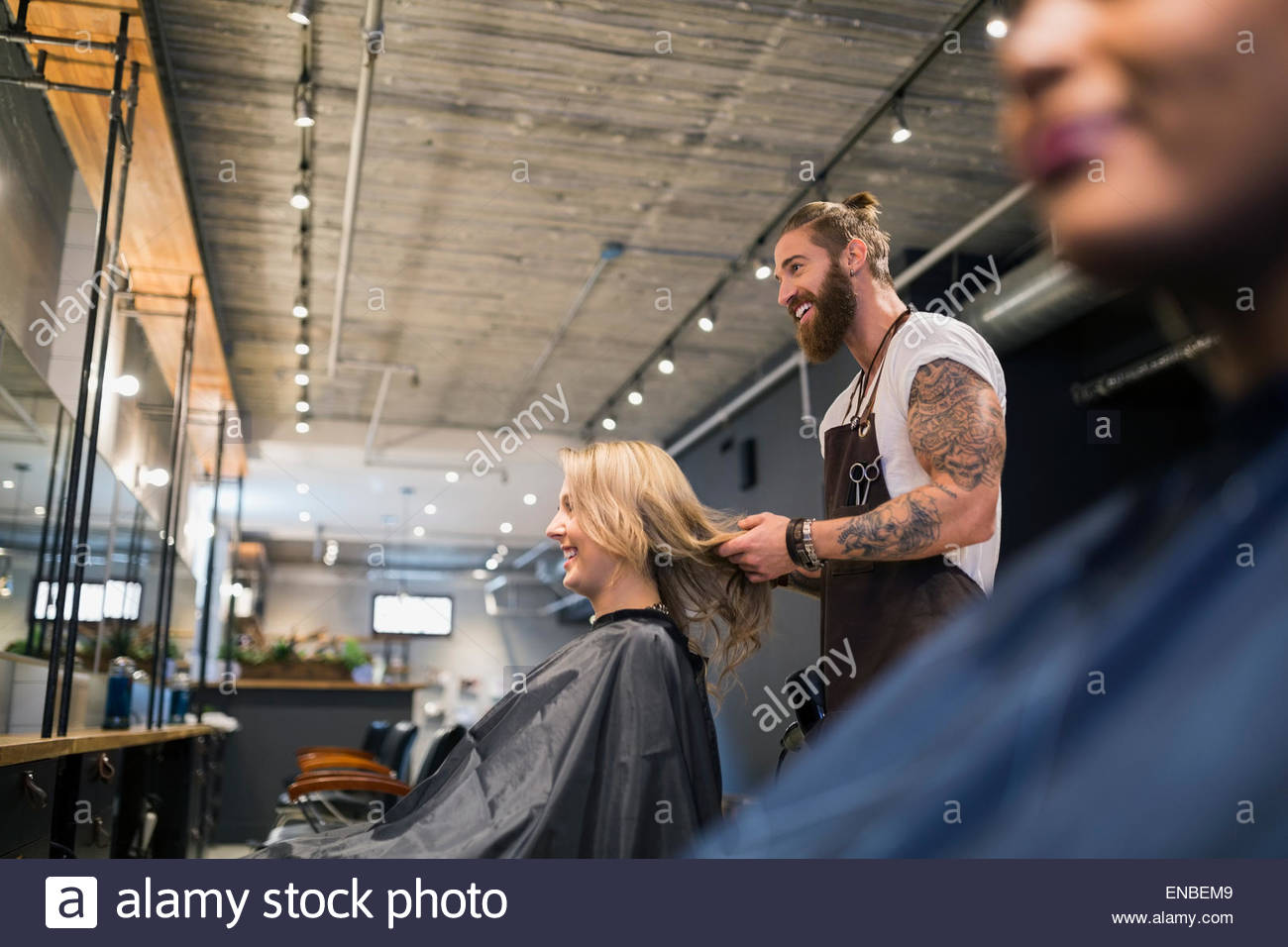 Male hairstylist styling womans hair in hair salon Stock Photo