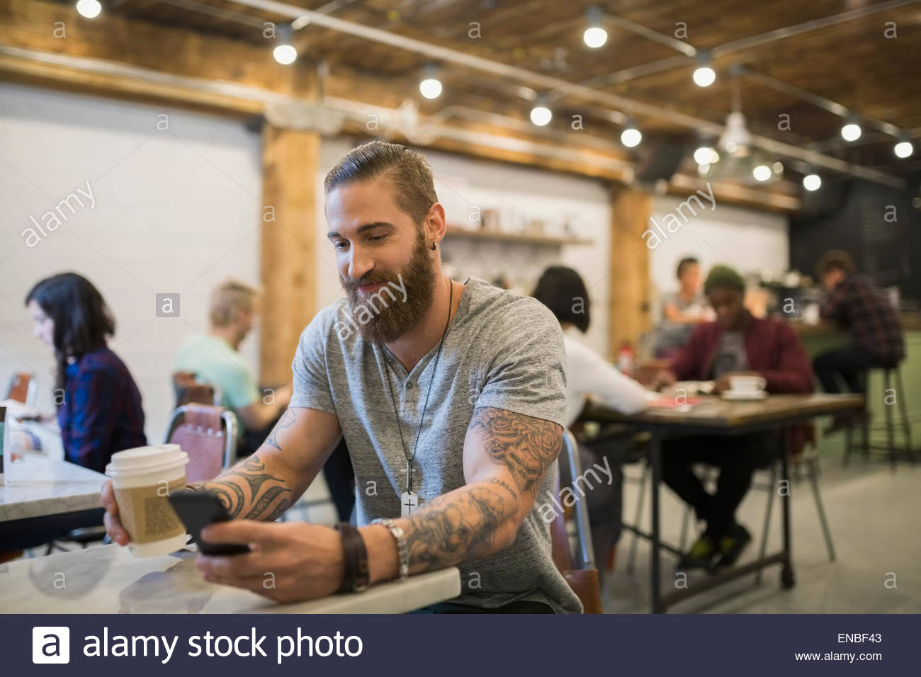 Bearded man with tattoos drinking coffee in cafe Stock Photo