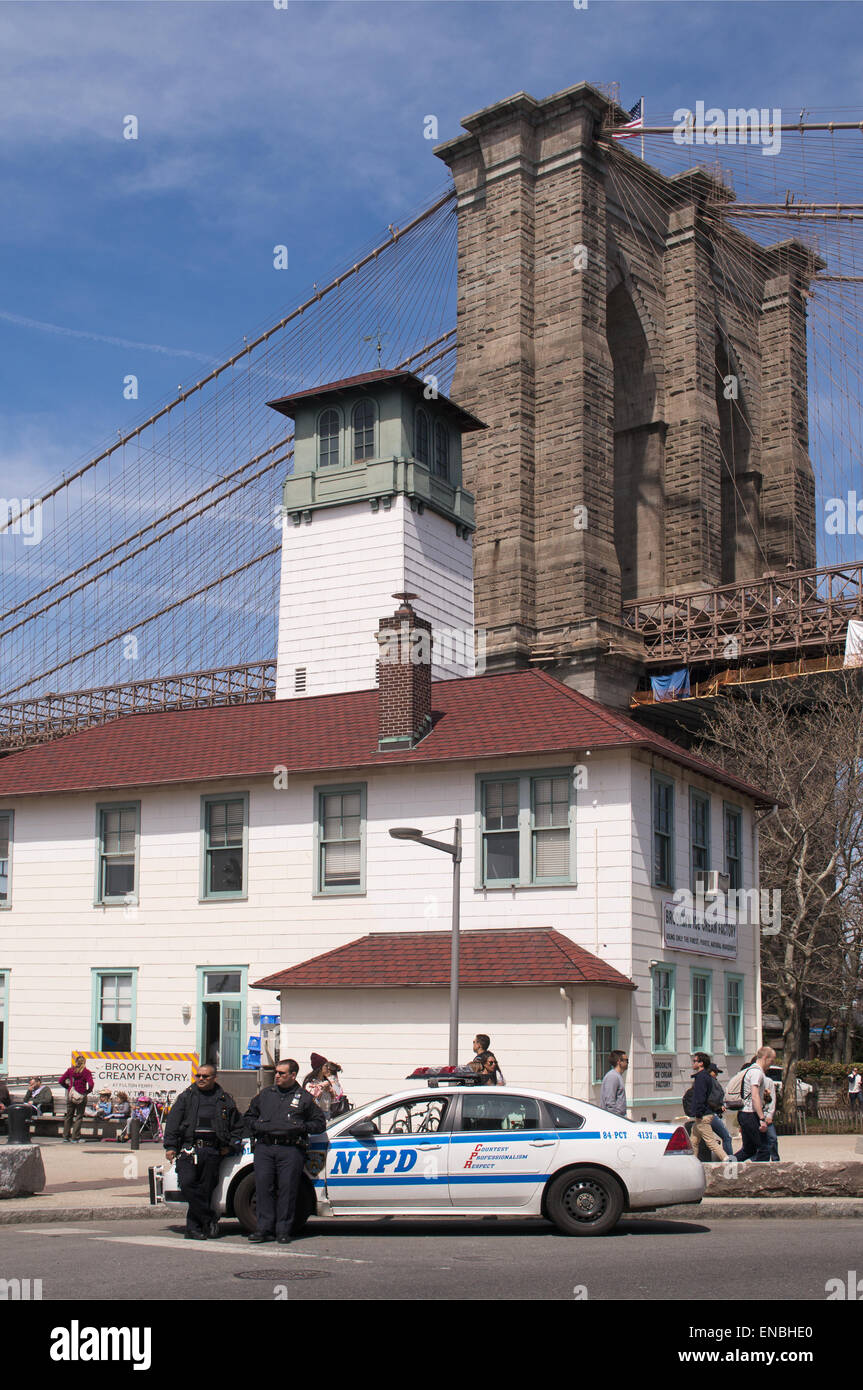 Two New York police officers and their NYPD car outside the Brooklyn Ice Cream factory building beneath Brooklyn bridge, NYC, US Stock Photo