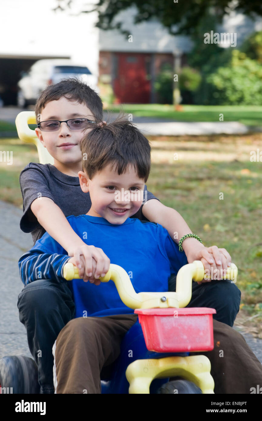 Two brothers, age seven and four ride a big wheel three wheeler in