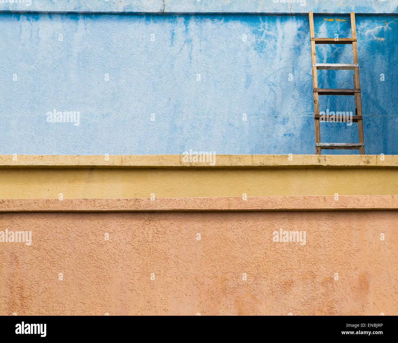 An old wooden ladder leaning against a blue stucco wall over yellow and