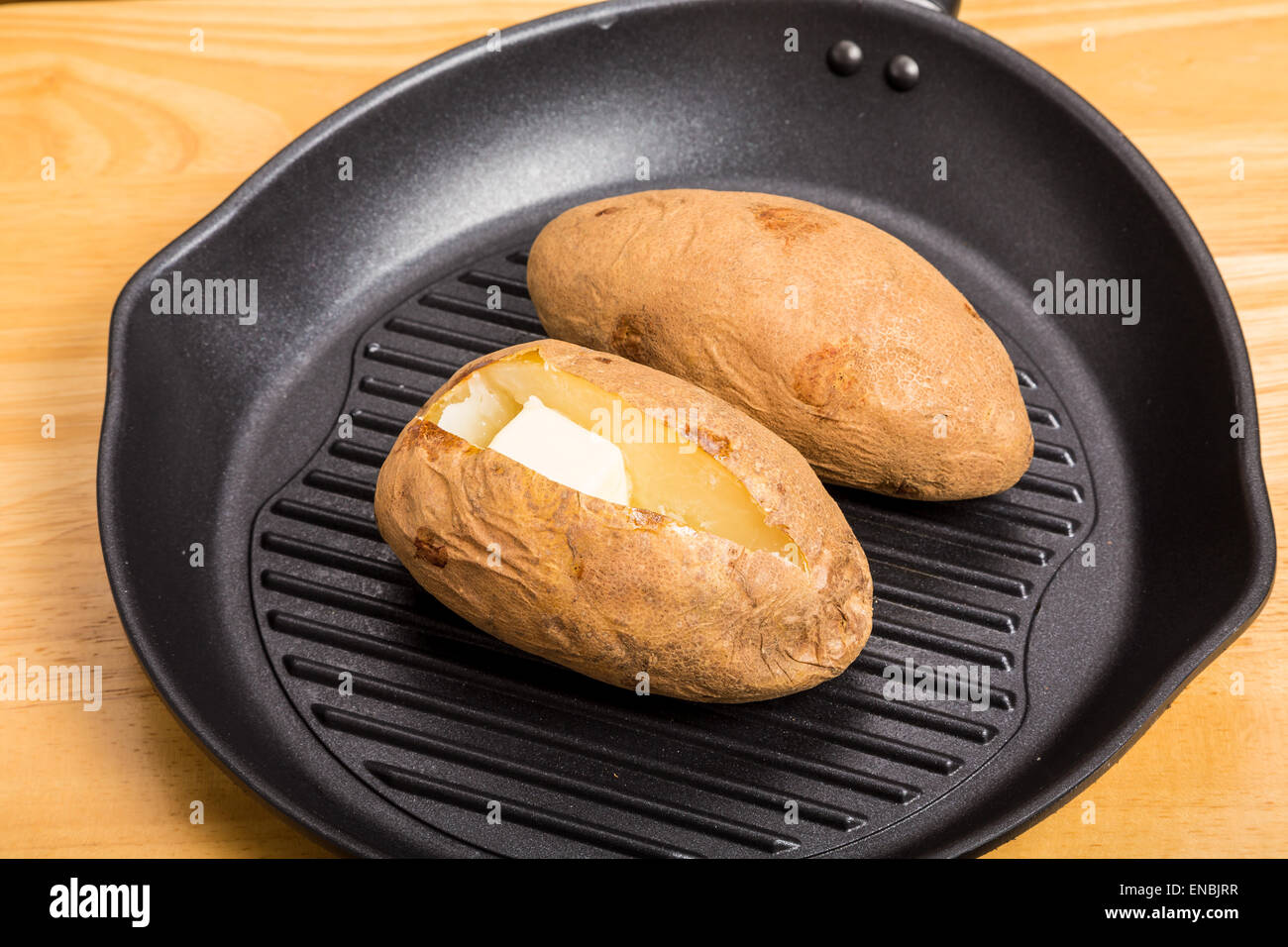 Two baked potatoes in a black iron skillet Stock Photo Alamy