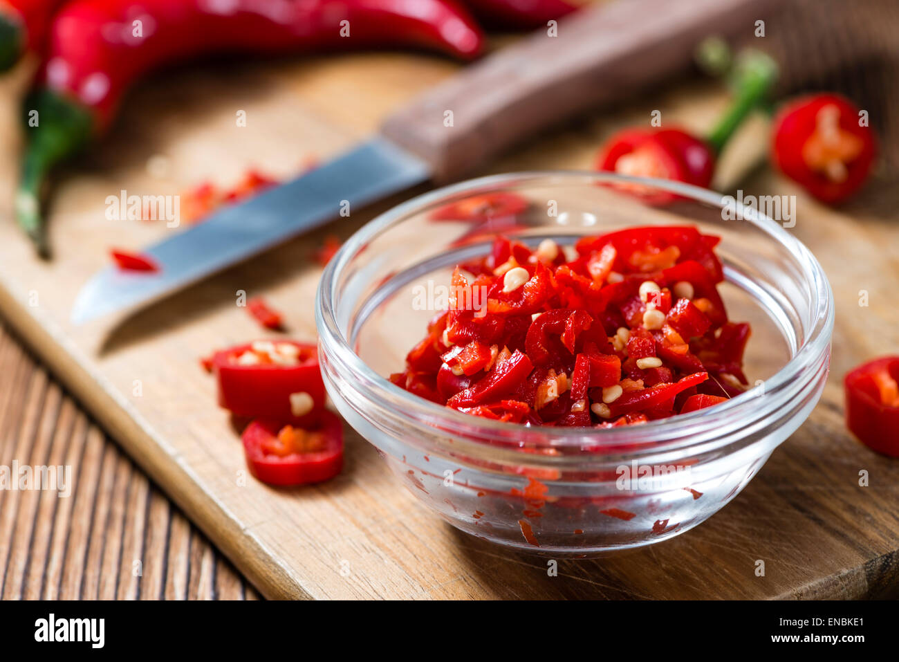 Cutted red Chilis (close-up shot) on wooden background Stock Photo