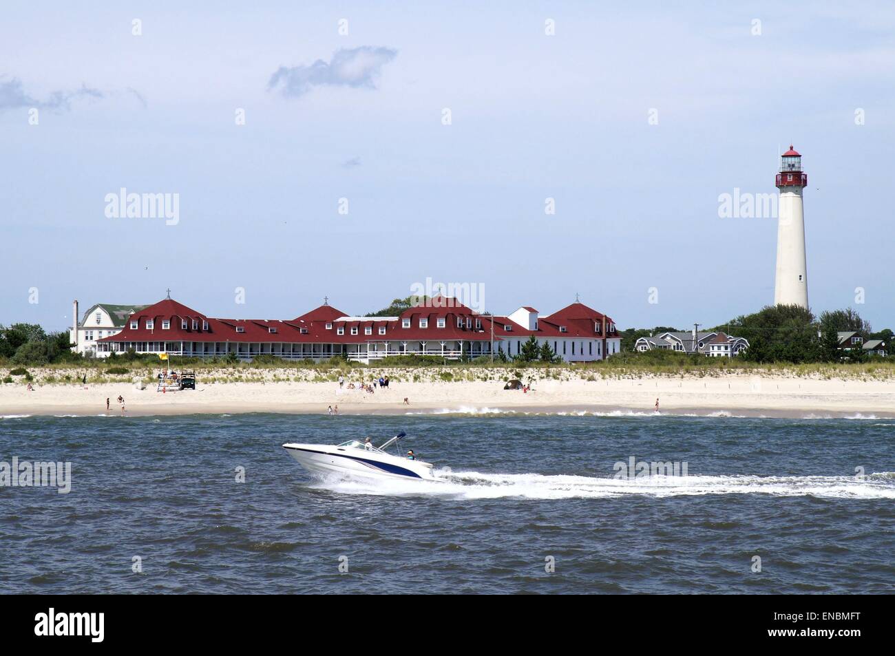 A boat passing shore with a lighthouse on a beach Stock Photo - Alamy