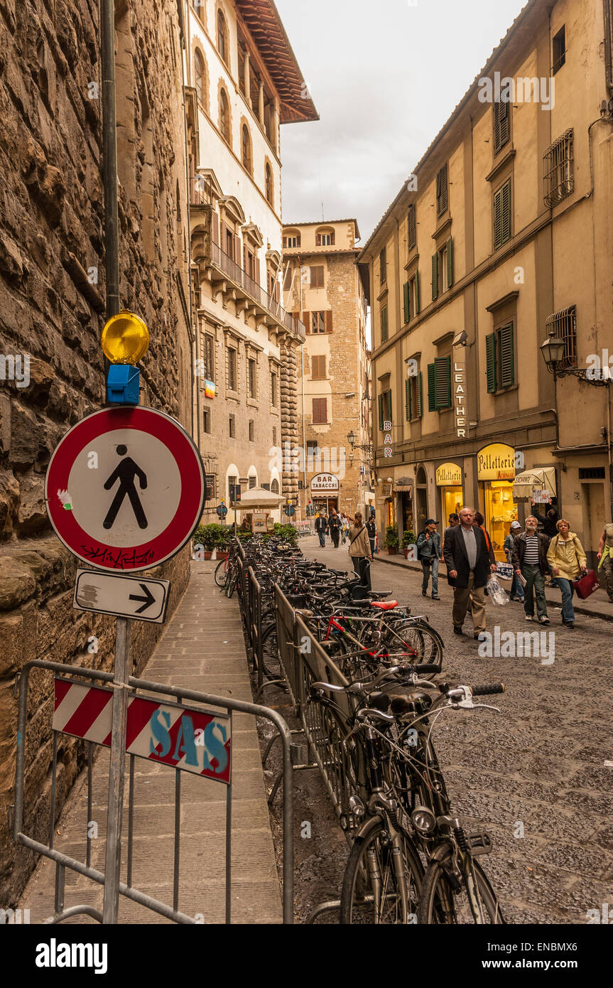 Bicycles parked ialong narrow street between two tall buildings in Florence, Italy Stock Photo