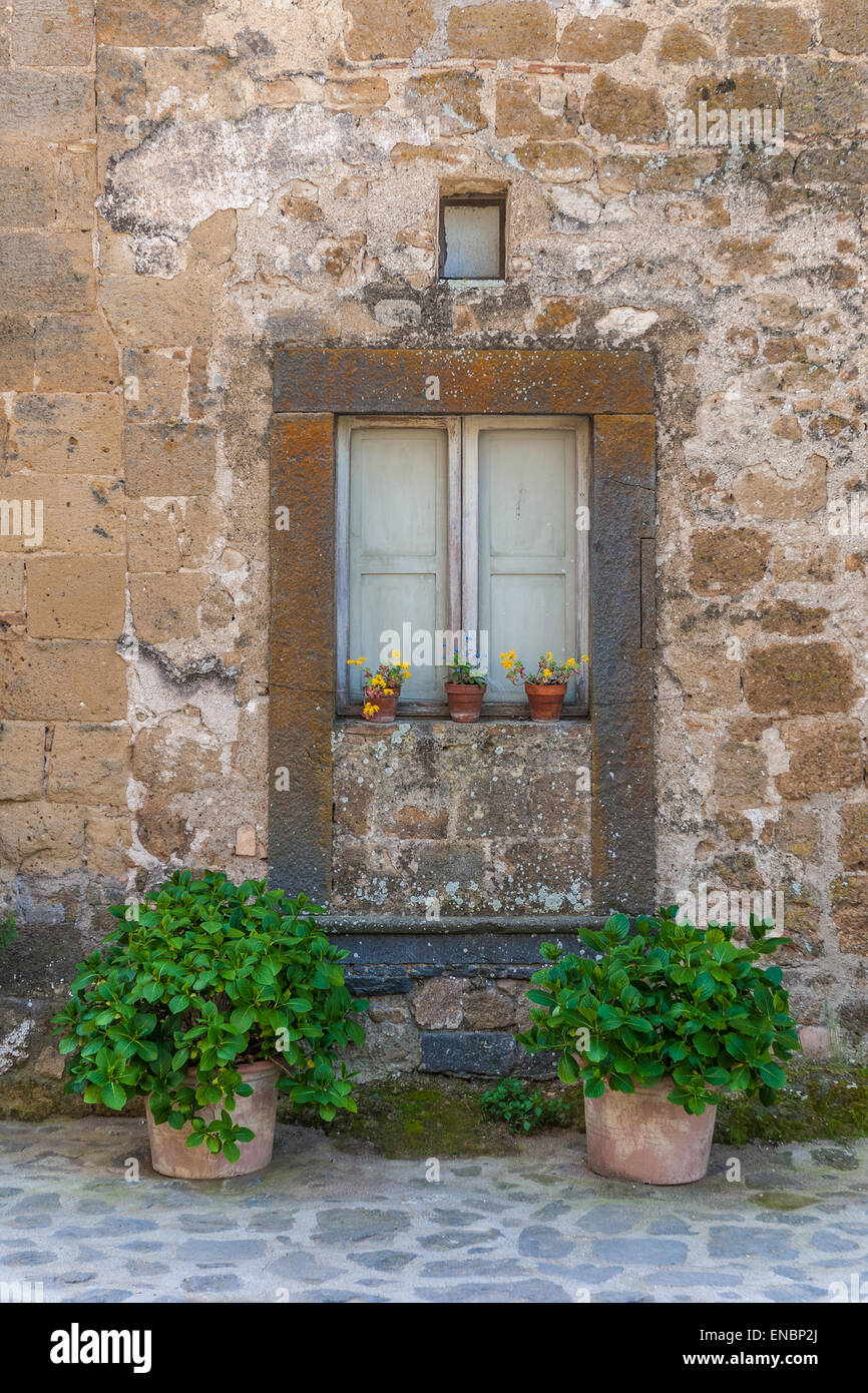 Potted plants below rustic window in Civita di Bagnoregio, Italy Stock Photo