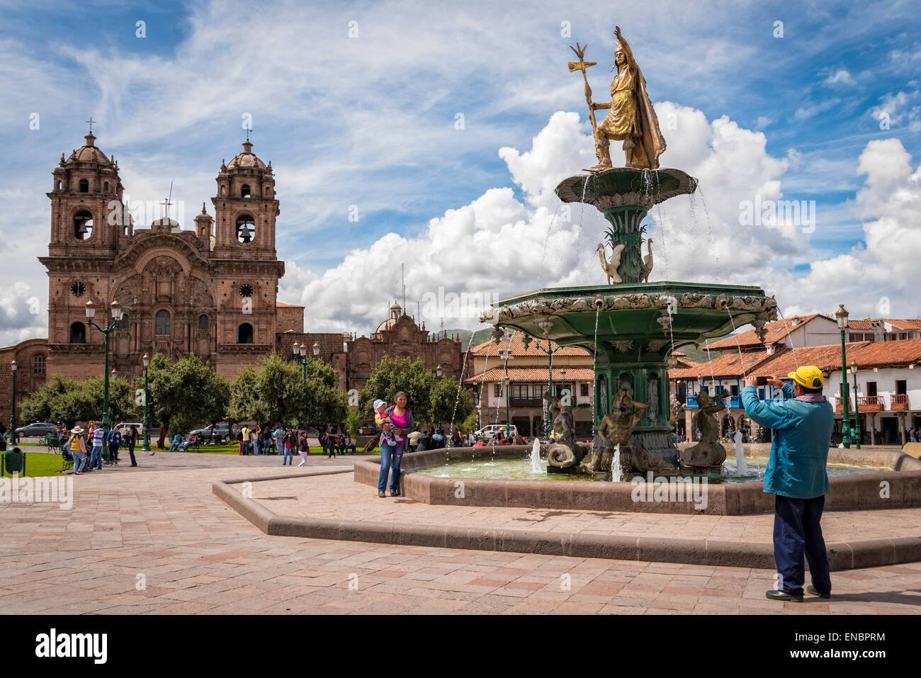 Visitors taking photo at fountain in Plaza de Armas with La Compañia church in background; Cusco. Peru. Stock Photo