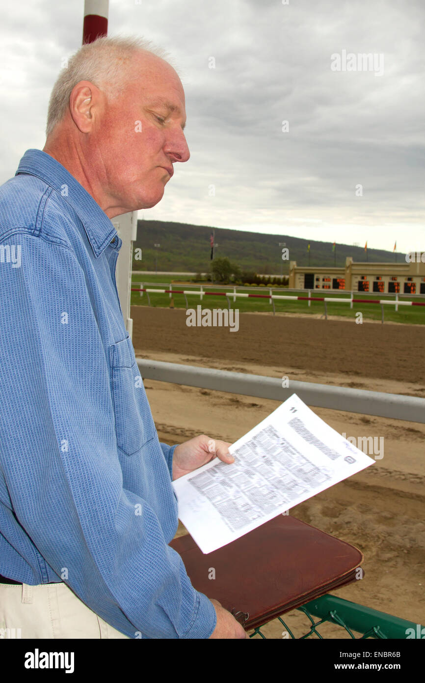 Man studying racing paper track side before races. Stock Photo