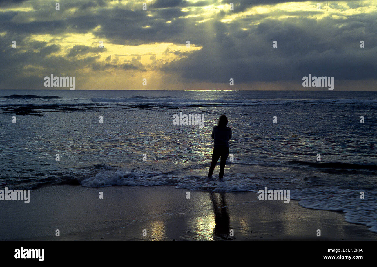 Silhouetted figure watching sea and stormy sky Stock Photo