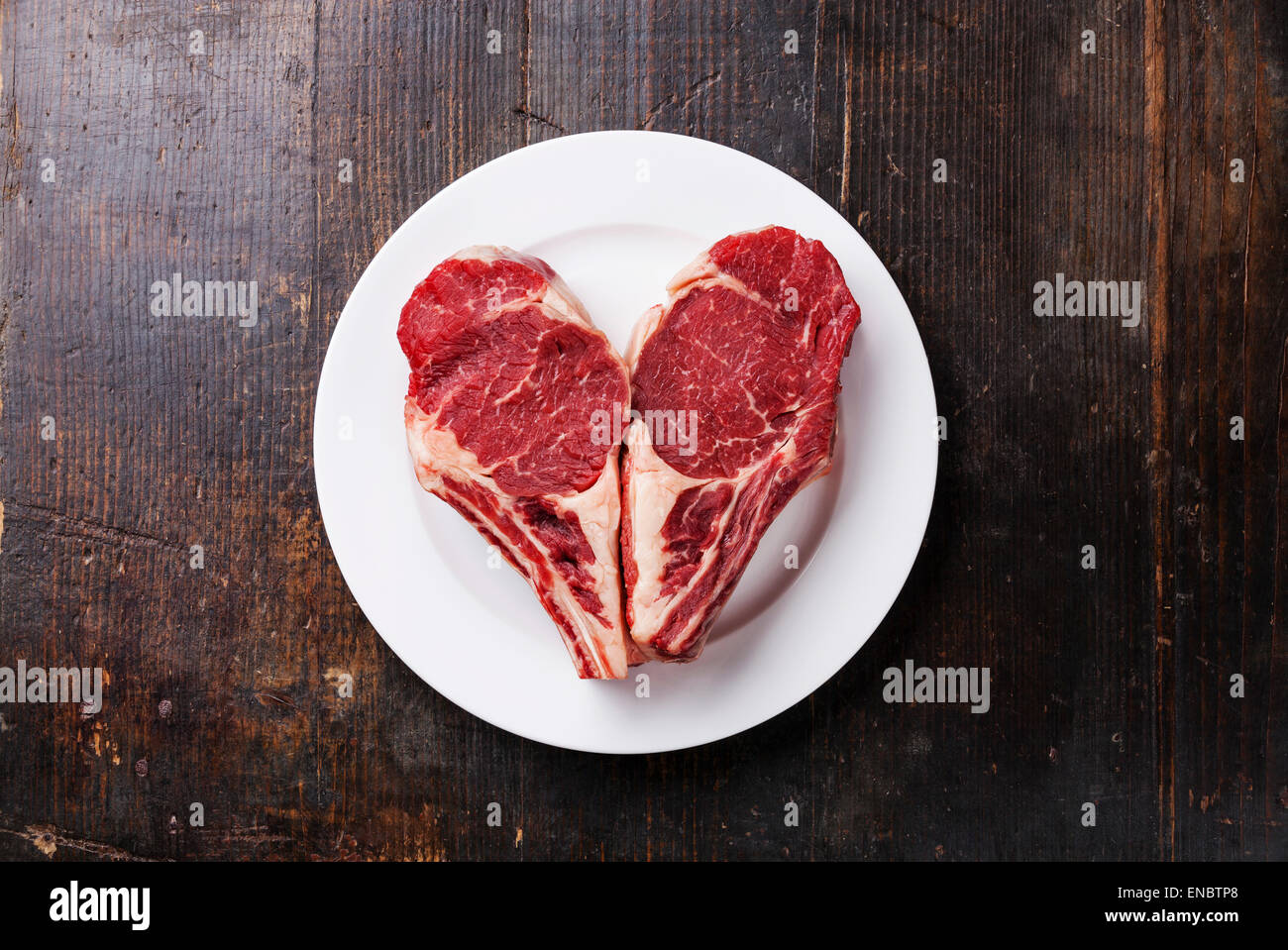 Heart shape Raw meat Ribeye steak entrecote on white plate Stock Photo