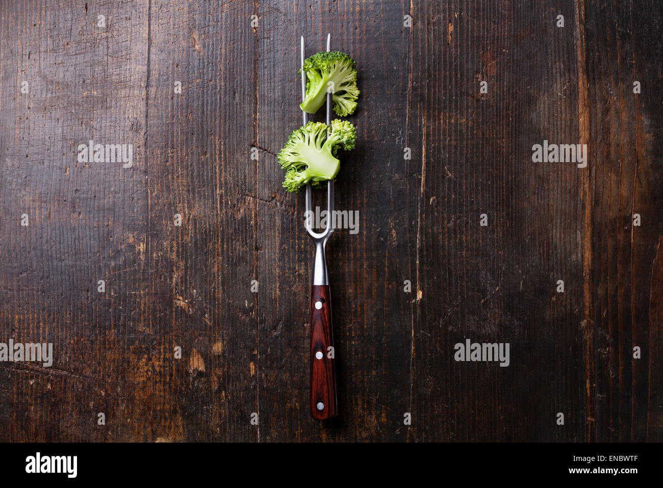 Fresh broccoli on meat fork on dark wooden background Stock Photo