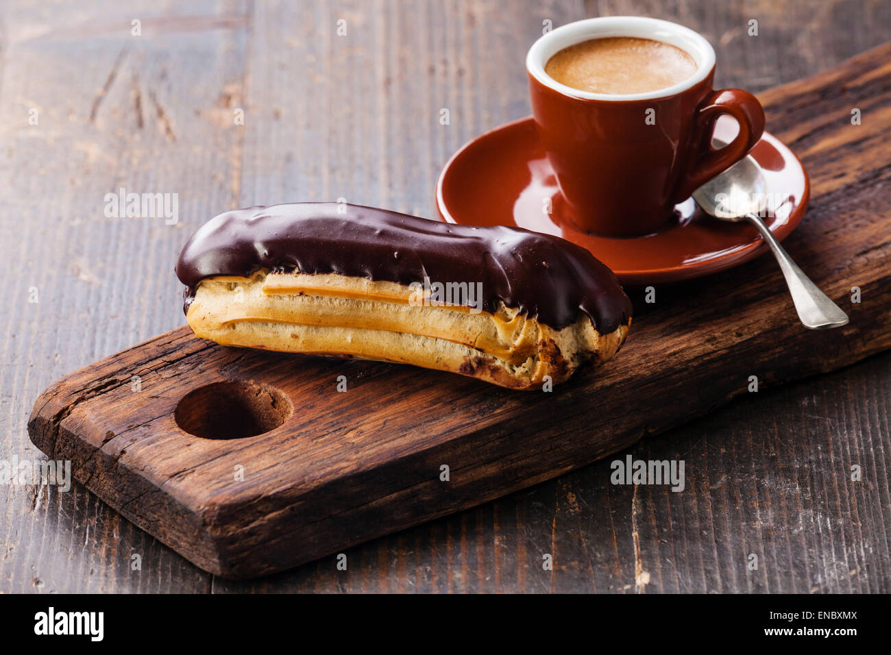 Chocolate eclair and coffee cup on dark wooden background Stock Photo