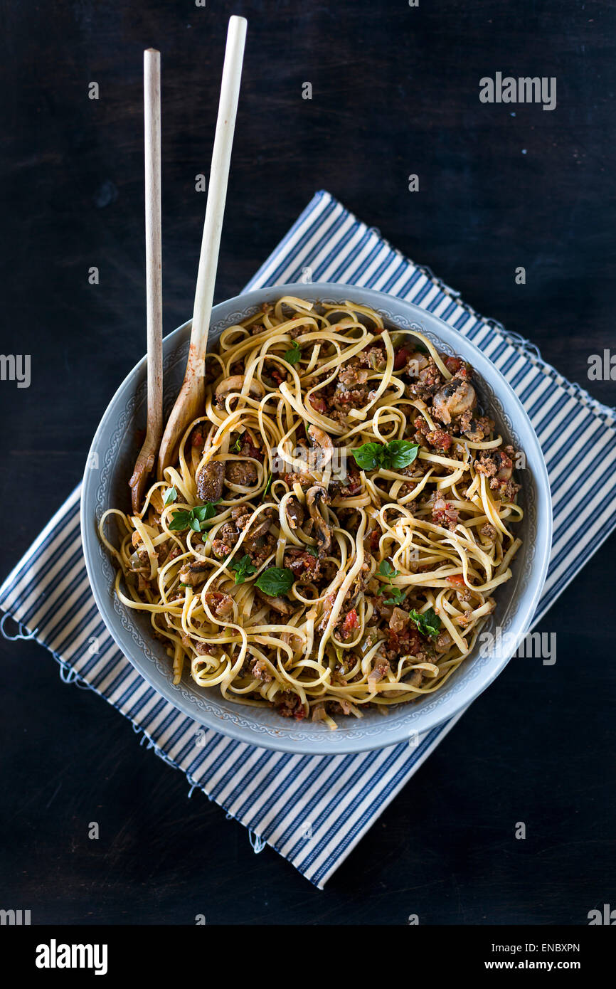 A large bowl of spaghetti bolognese displayed with two wooden spoons. Ready to be served. Stock Photo