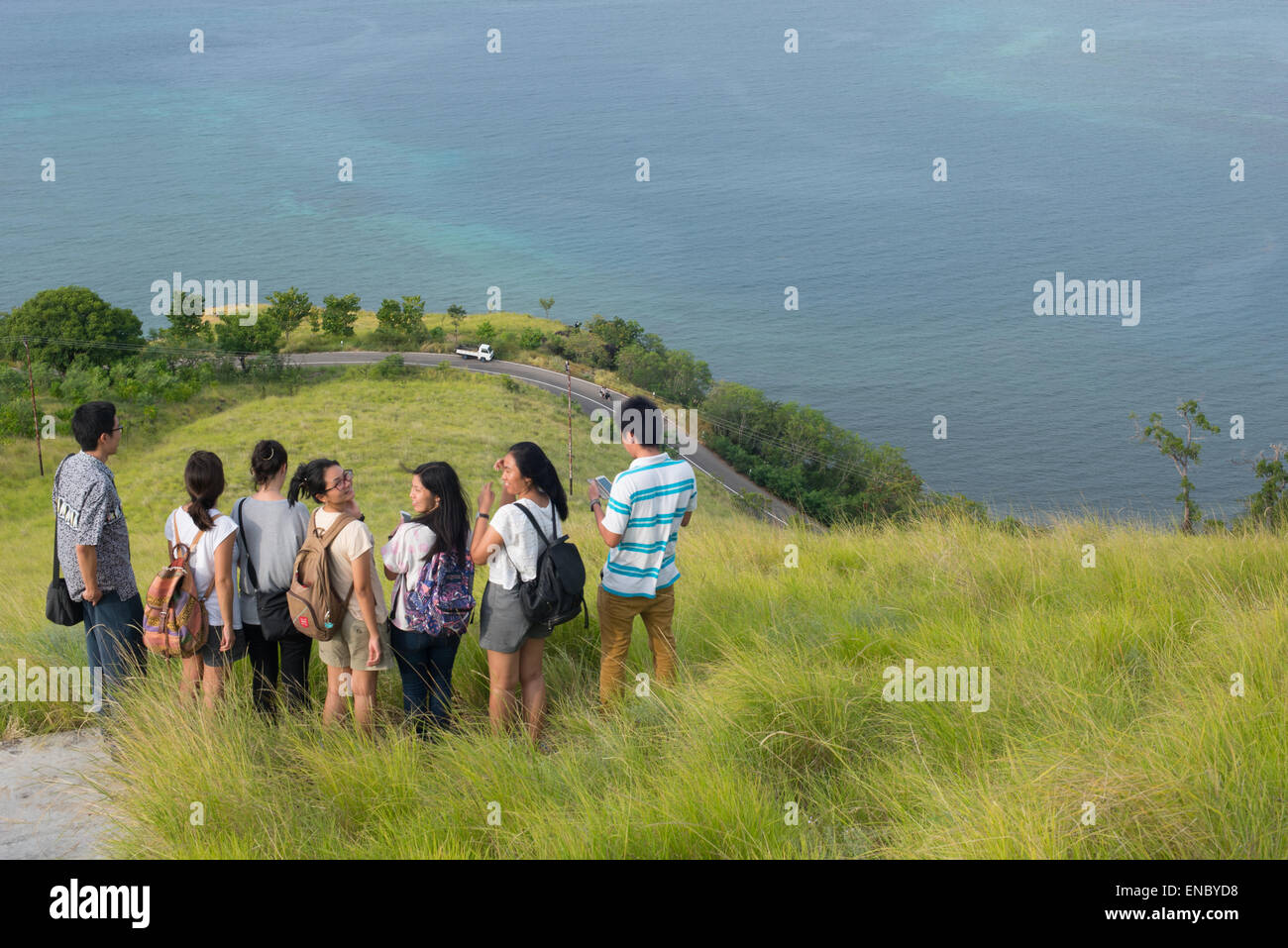 Young people enjoys panoramic view at Bukit Tanjung Kajuwulu, Maumere, Flores, Indonesia. Stock Photo