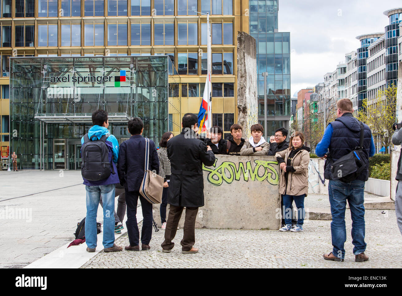 Tourists photographing with remnants of the Berlin Wall, in front of ...