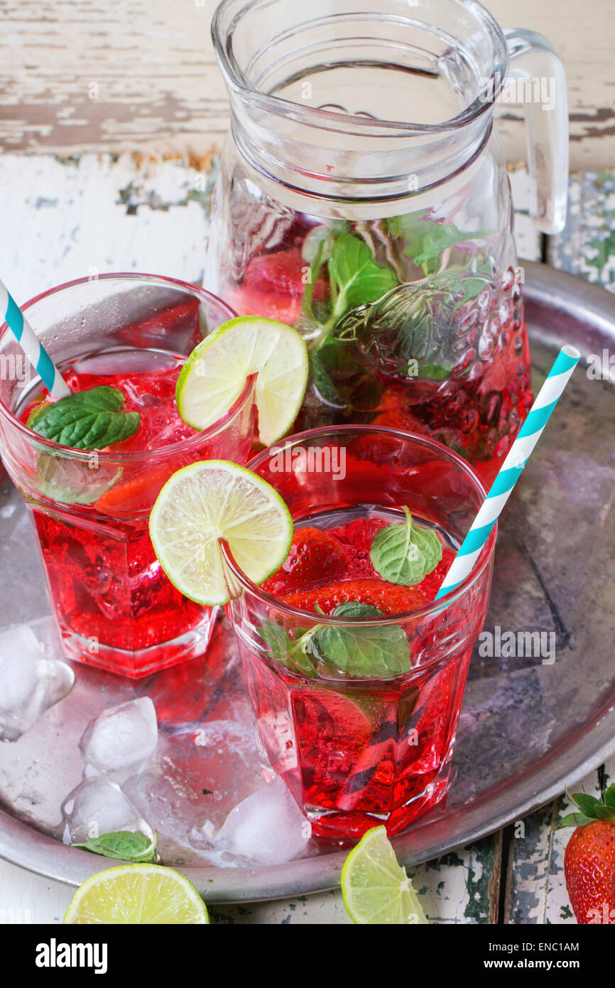 Two glasses with retro cocktail tubes and glass jug of homemade