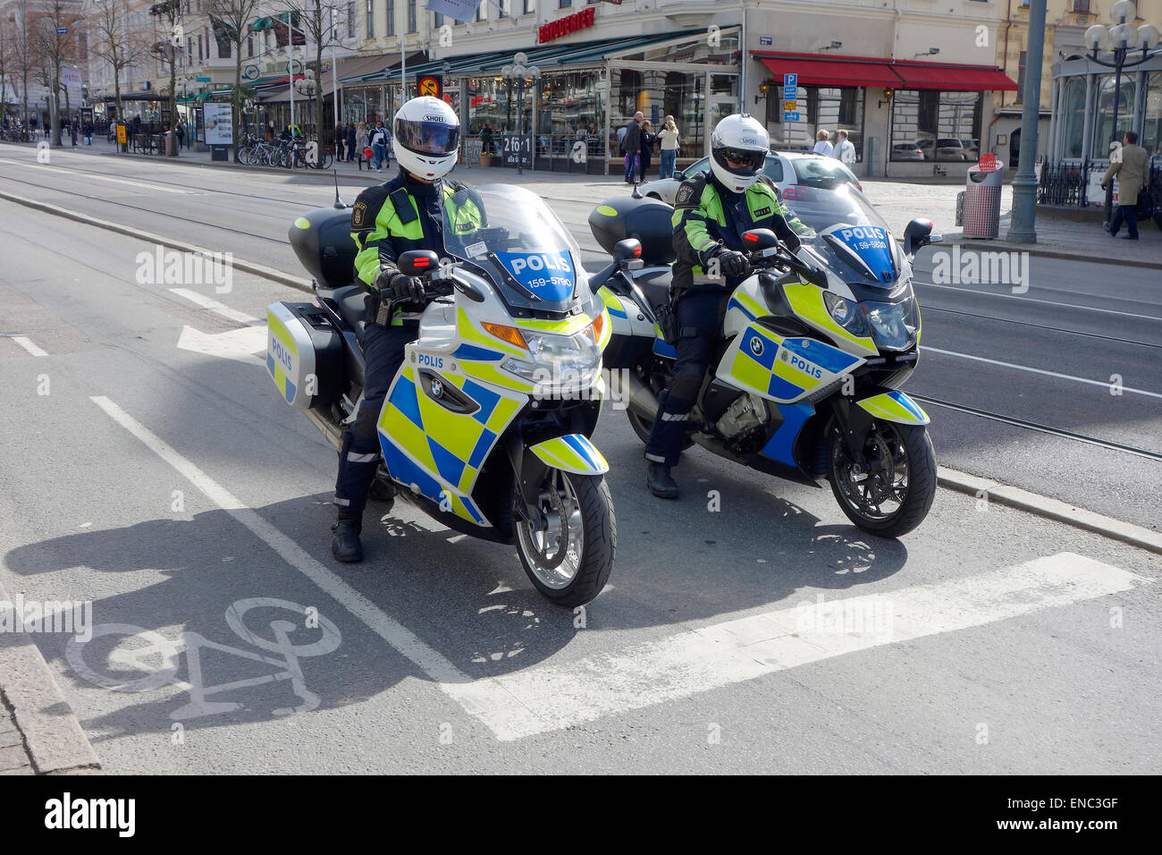 Two Swedish police officers patrolling on motorcycles stop and wait for green traffic light Stock Photo