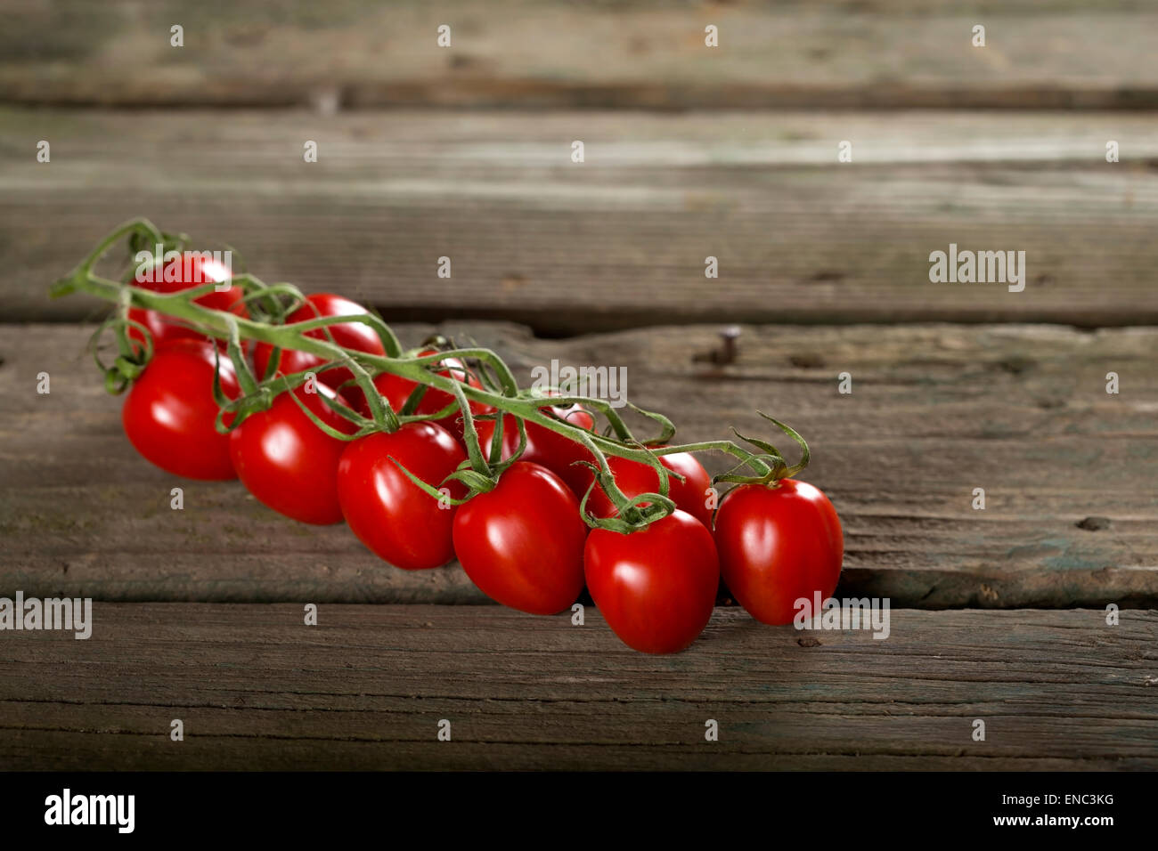 Some cherry tomatoes on a wooden surface Stock Photo