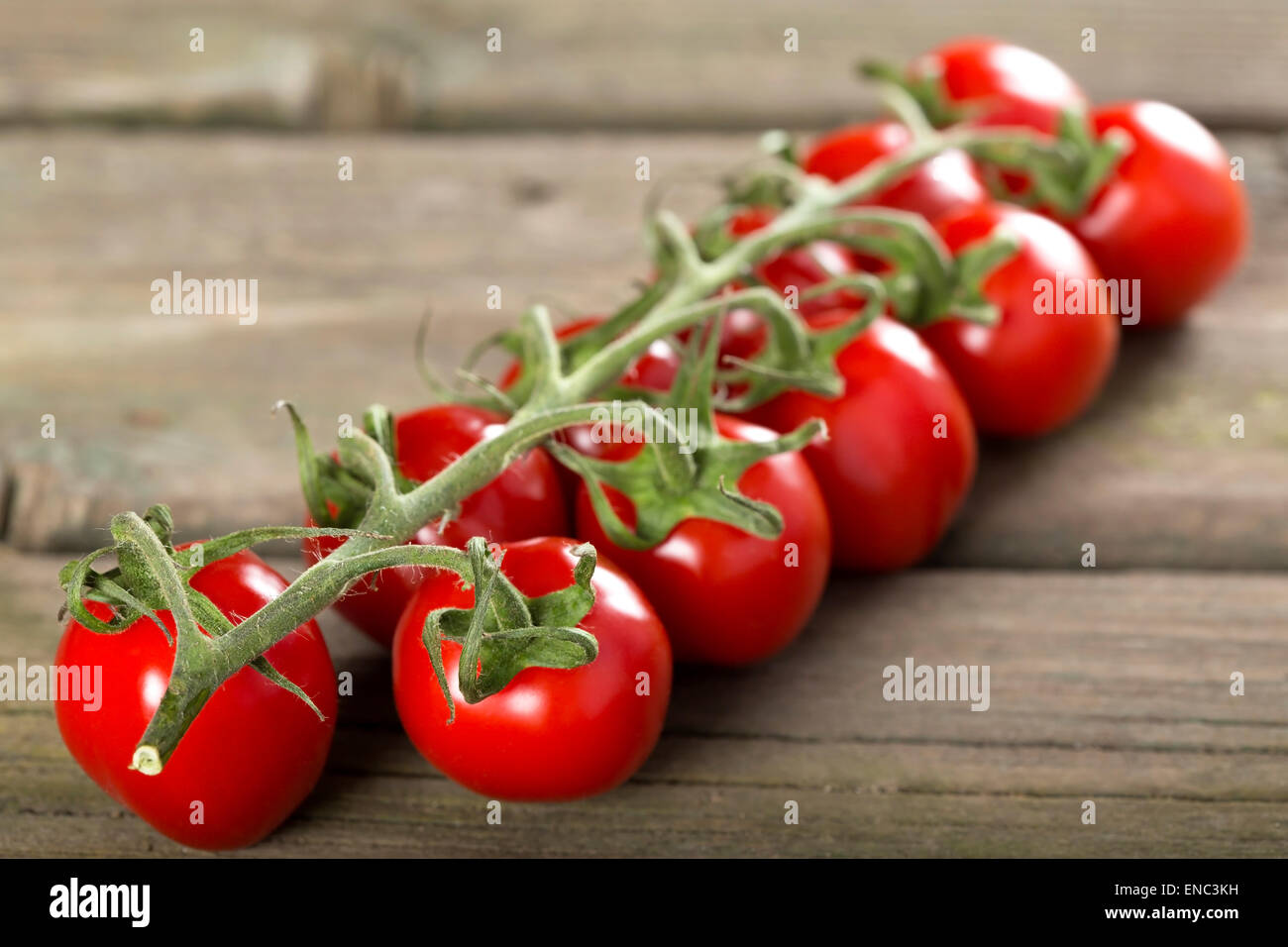 Some cherry tomatoes on a wooden surface Stock Photo