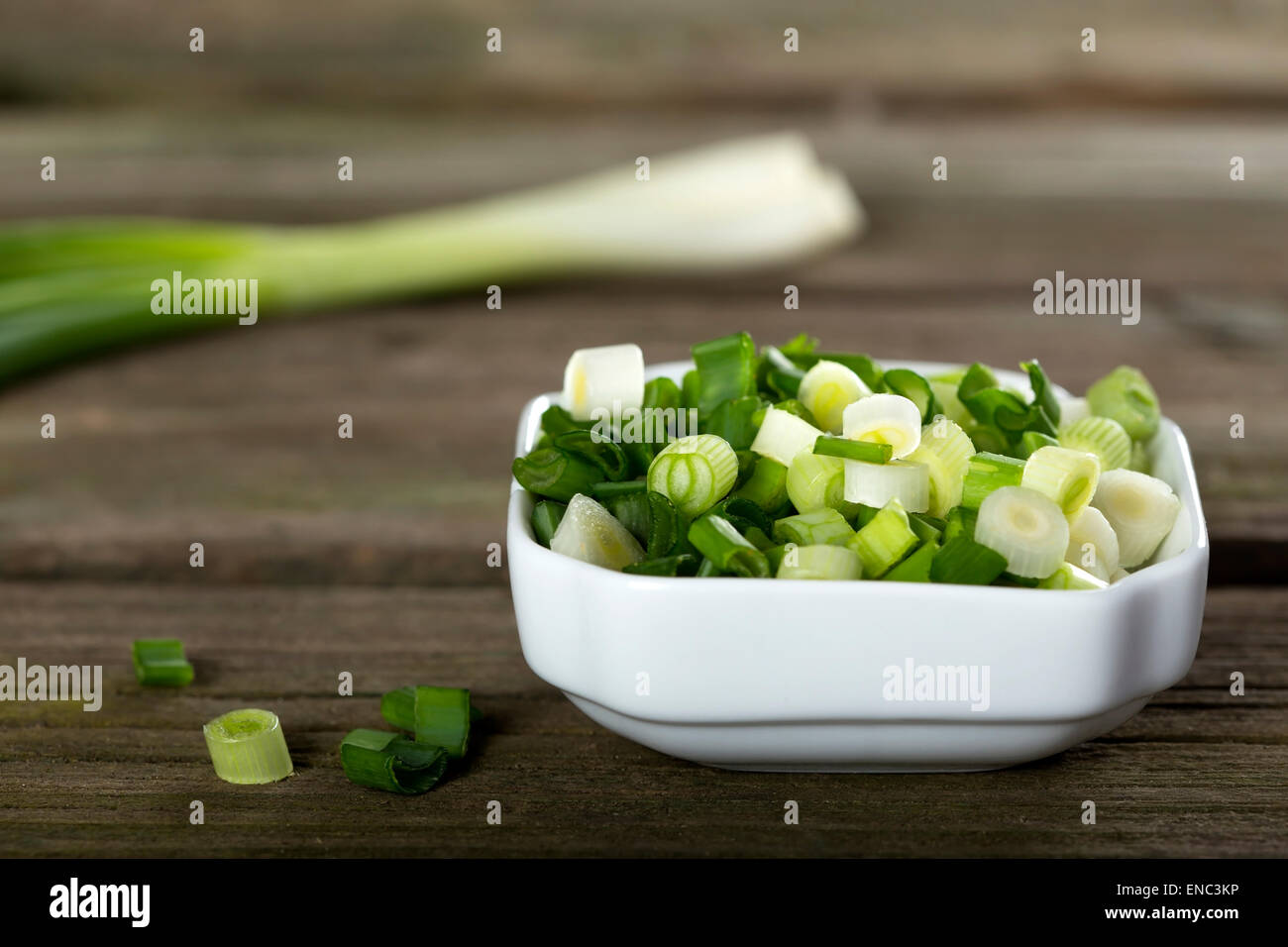 Fresh sliced scallions in white bowl on wooden background Stock Photo