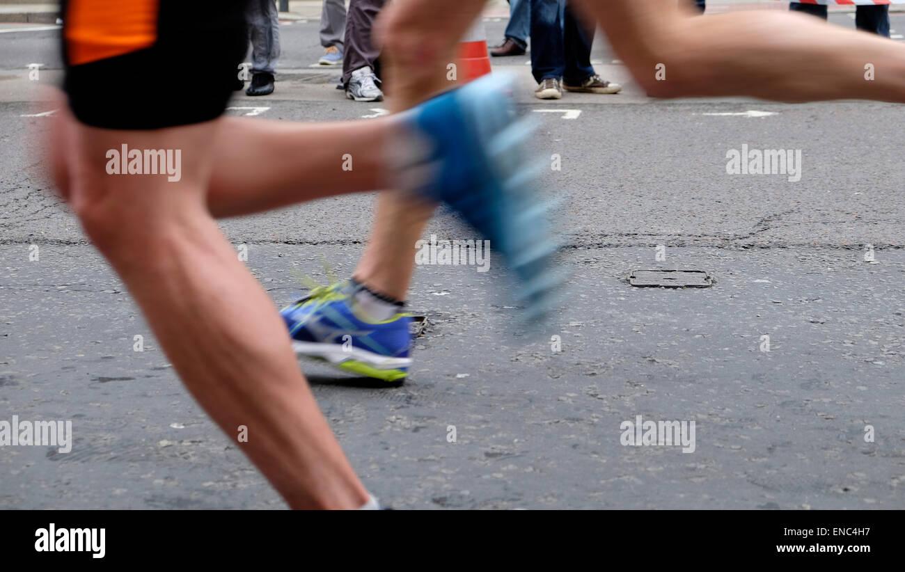 Blurred motion closeup blurry blur detail of legs shoe shoes of London Marathon runner runners competitor competitors wearing shorts running fast along Upper Thames Street with speed in the City of London UK   KATHY DEWITT Stock Photo