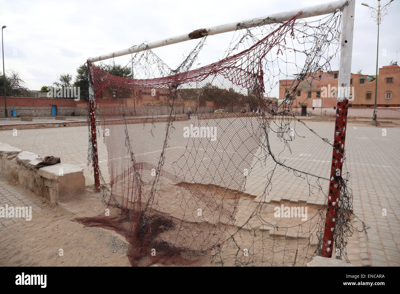 Football goalposts with a very worn net alongside a concrete pitch in Marrakech, Morocco Stock Photo