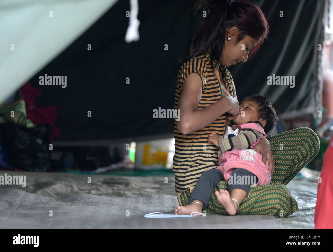 Kathmandu, Nepal. 2nd May, 2015. A woman feeds a baby in Kathmandu, Nepal, on May 2, 2015. The death toll from last Saturday's powerful earthquake in Nepal reached 6,659 and a total of 14,062 others were injured, the country's home ministry said on Saturday. Credit: Qin Qing/Xinhua/Alamy Live News Stock Photo