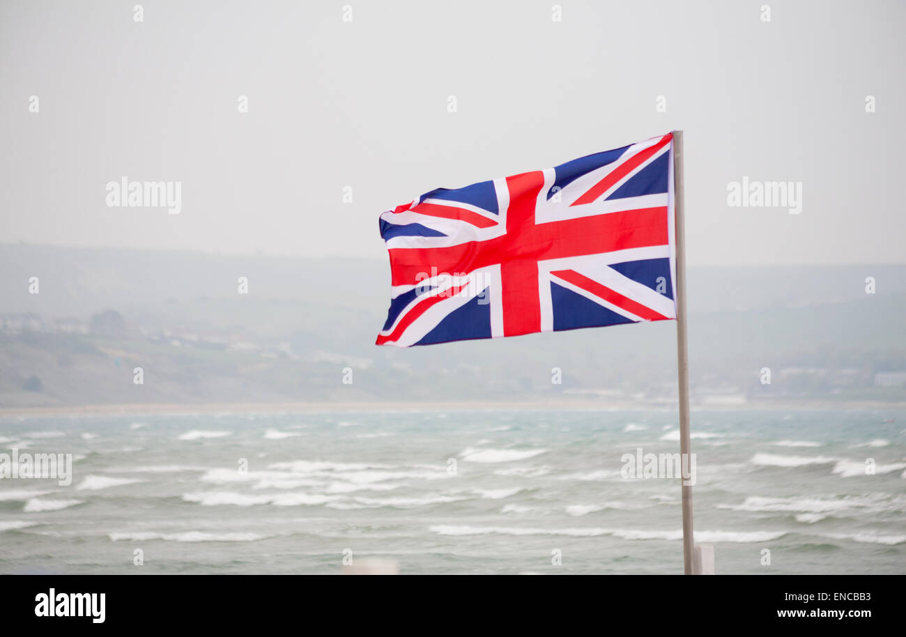 Weymouth, Dorset, UK. 2 May 2015. UK Weather: Cold windy day at Weymouth beach, Dorset, UK on the first day of the long Bank Holiday weekend. The Union Jack flag blows in the wind on the day of the Royal birth with Kate giving birth to a baby girl. Credit:  Carolyn Jenkins/Alamy Live News Stock Photo