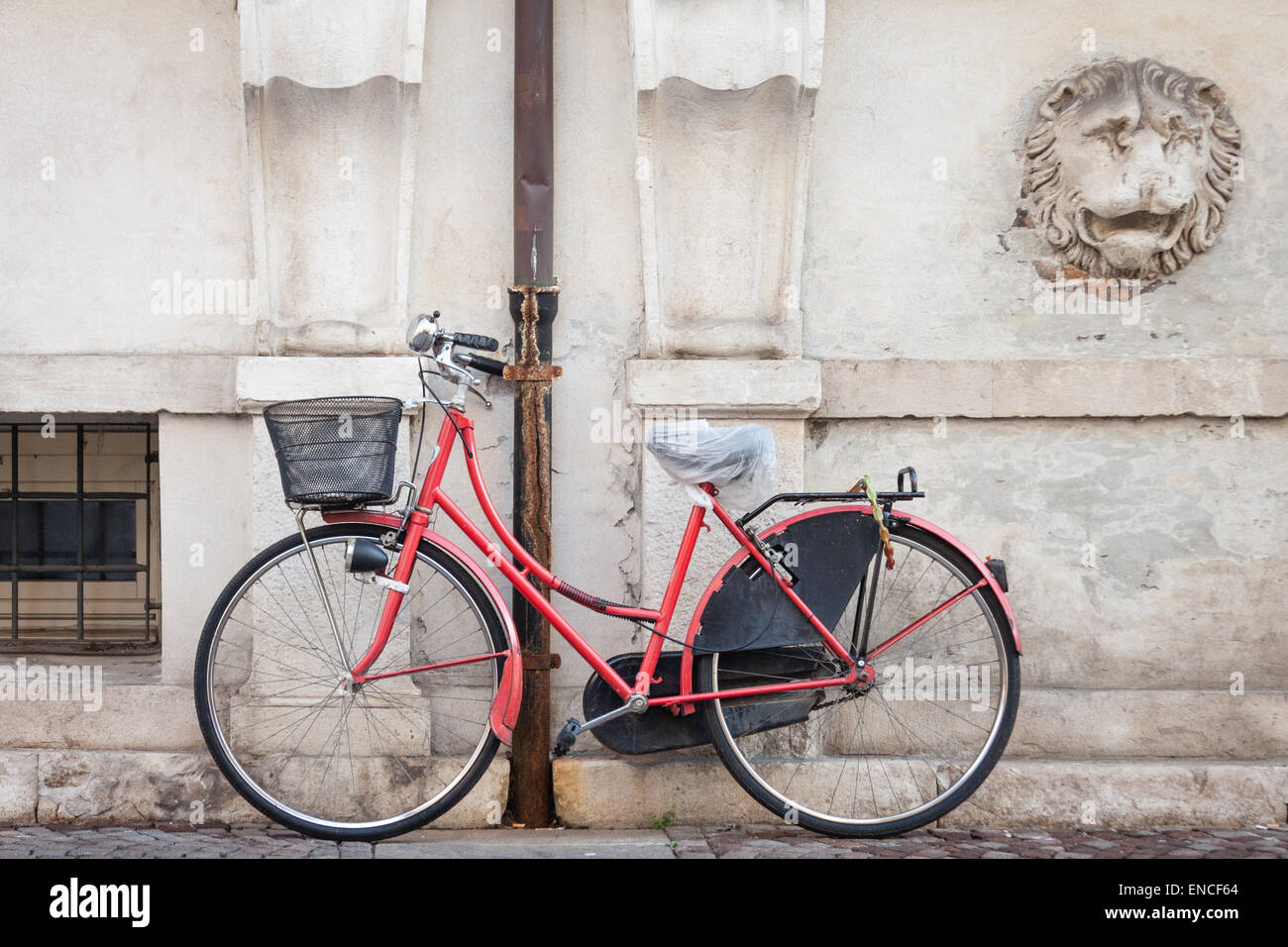 red bicycle leaning against a wall in Ferrara, Italy Stock Photo