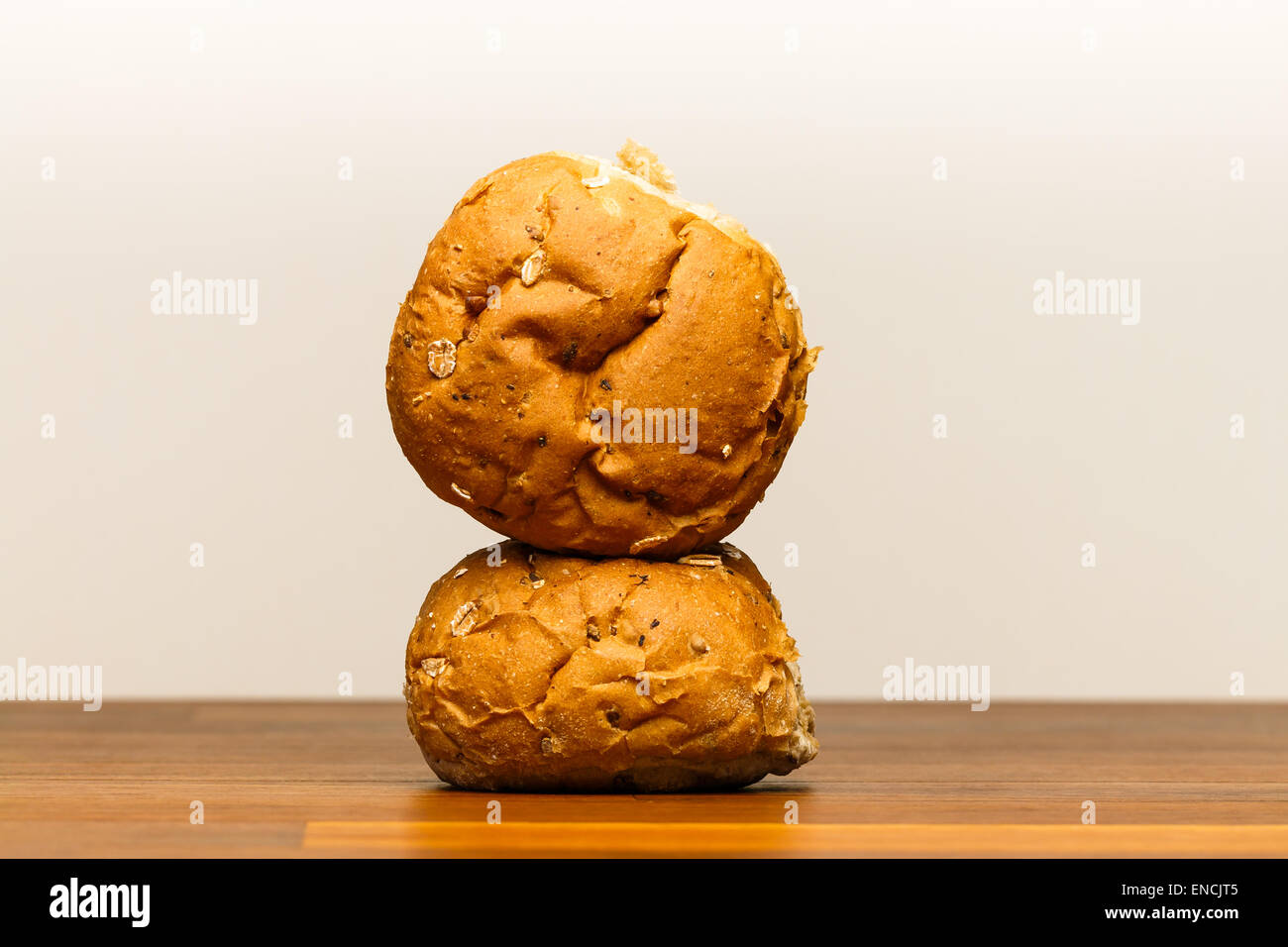 Two spelt buns on wooden surface. One is on its side on top of the other. Spelt is also known as dinkel or hulled wheat. Spelt i Stock Photo