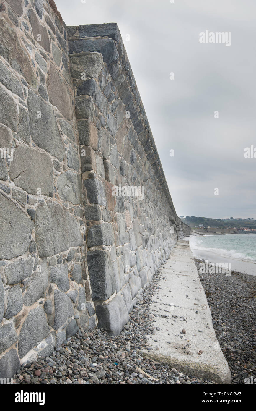 Granite sea wall, with curved top, on the west coast of Guernsey, Channel Islands. Stock Photo
