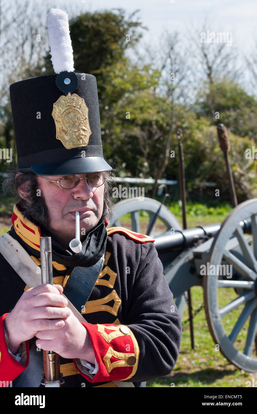 A Napoleonic infantry soldier resting and smoking his pipe in front of Royal Horse  Artillery canon. Stock Photo